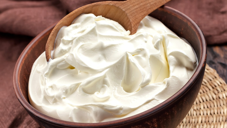 Bowl of softened cream cheese with wooden spoon