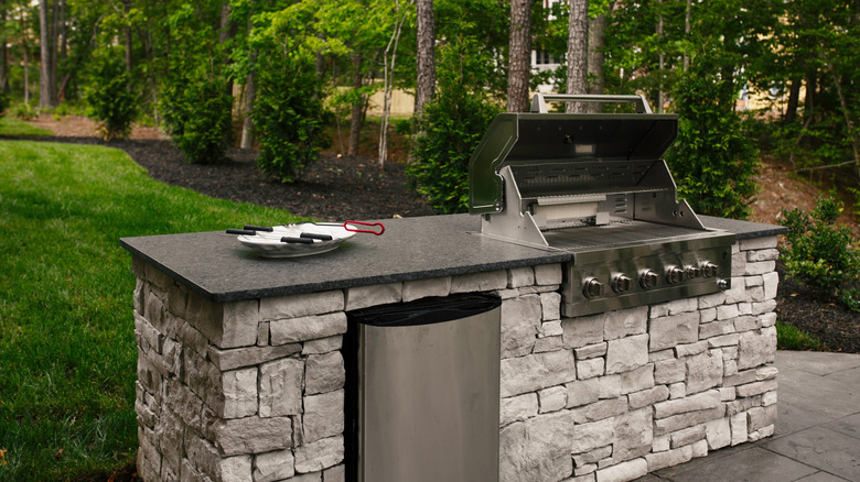 backyard stone grill setup with a plate with tongs resting on it