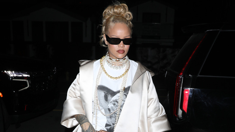 Rihanna outside Giorgio Baldi restaurant in a white coat, Tupac shirt, many pearls, and large sunglasses