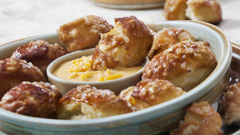 Bowl of salted pretzel bites with cheese dip.