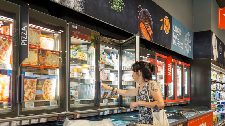 A young person reaches into the freezer section for a box at Aldi