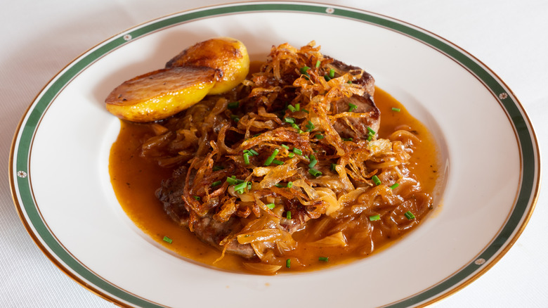 Plate of zwiebelrostbraten with roasted potatoes.