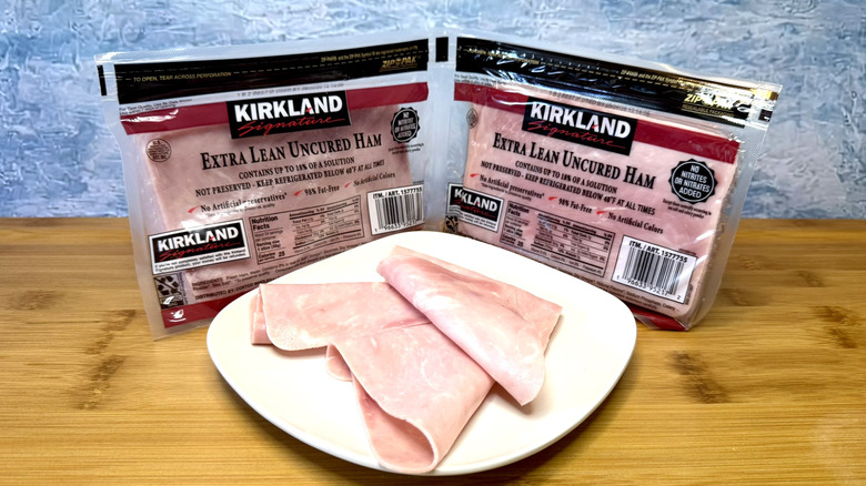 Kirkland Signature sliced ham on white plate with packages behind.