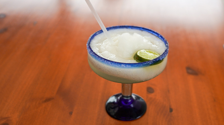 Frozen margarita in a blue-rimmed glass.