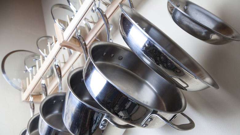 Stainless steel pots and pans hanging from a wall rack