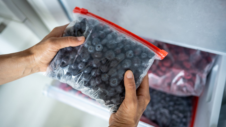 A person grabs out a sealed bag of frozen fruit from a freezer