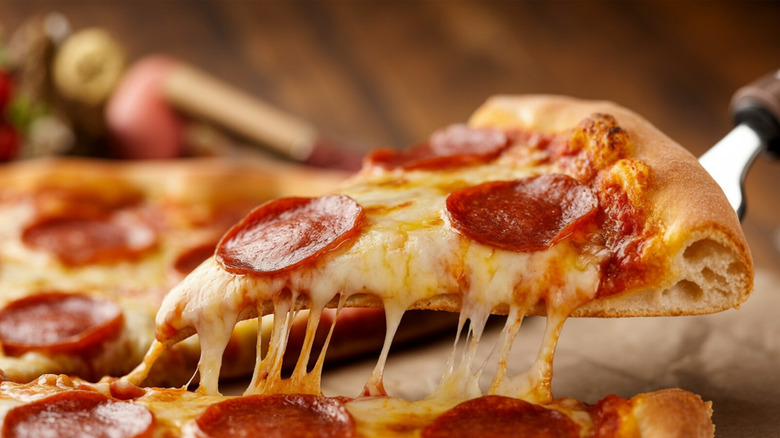 Cheese stretching as a slice of pepperoni pizza is pulled from a pie