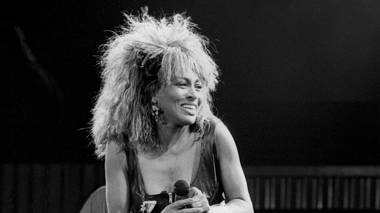 Tina Turner smiling on stage during her 1990 "Foreign Affairs" tour.