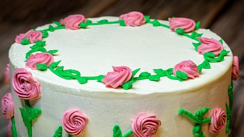 Detail of a white frosted cake with pink frosting roses