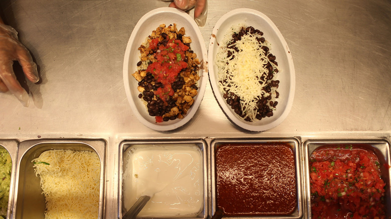 Chipotle worker filling two burrito bowls