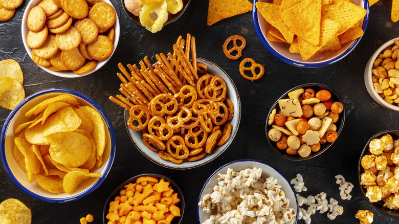 Overview of variety of generic snacks such as pretzels, crackers, tortilla chips, rice cracker mix, potato chips, popcorn, and more.
