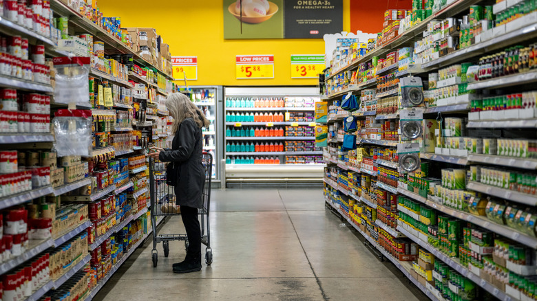 Woman shopping the canned goods at an H-E-B