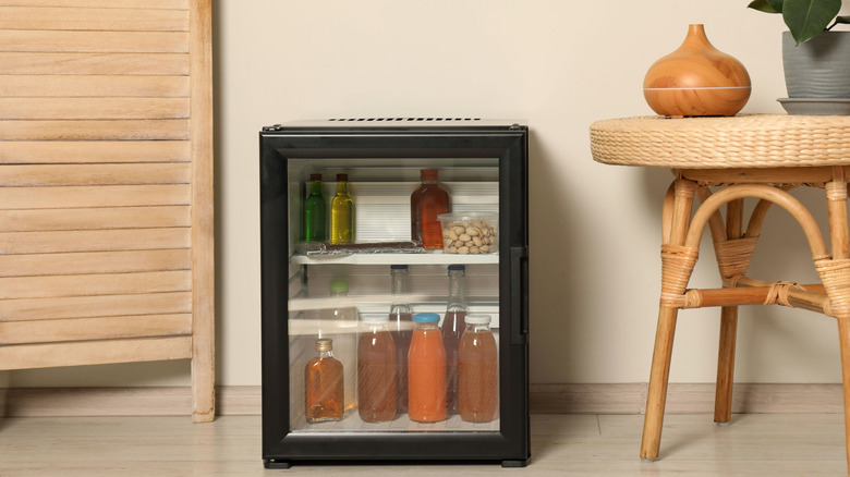 Mini fridge with drinks next to table