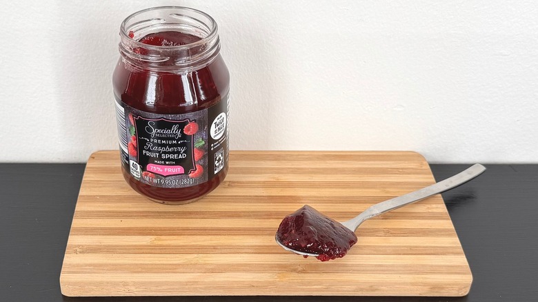 jar and spoon with Specially Selected Premium Raspberry Fruit Spread on a cutting board
