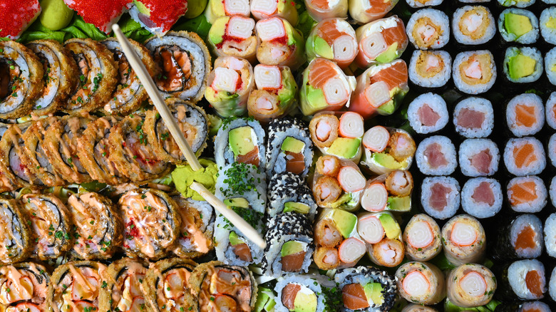 Rows of various pieces of sushi with chopsticks