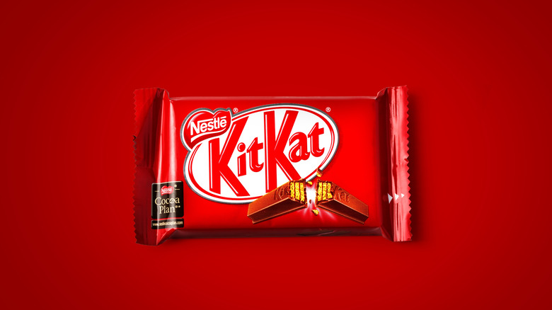 A single Kit Kat bar in its red wrapper, on a red background