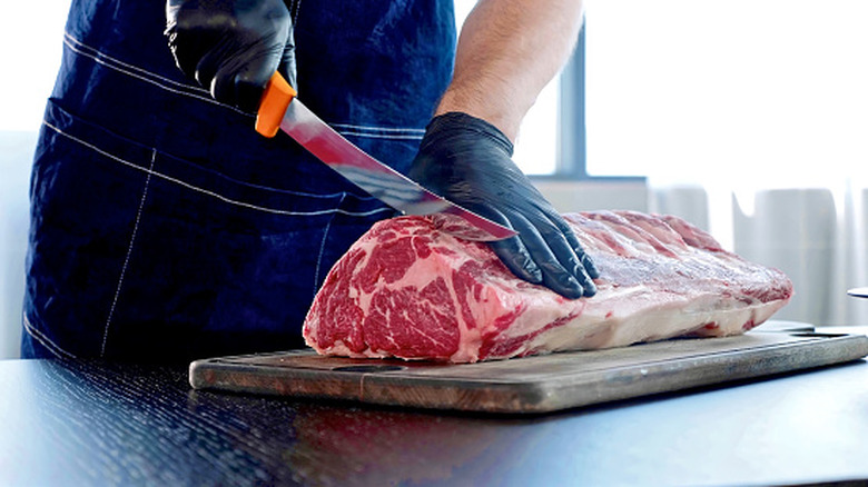 A chef cutting steaks from a large piece of beef