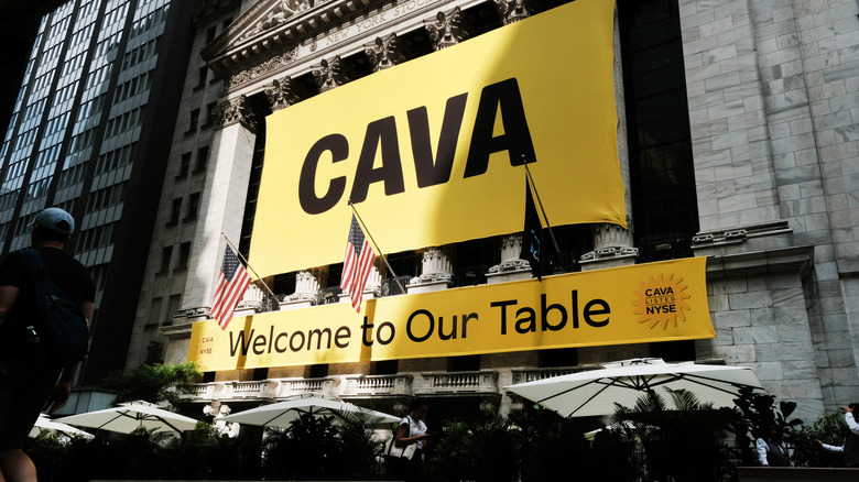 A yellow banner on the front of the NY Stock Exchange that says "Cava: Welcome to our table"