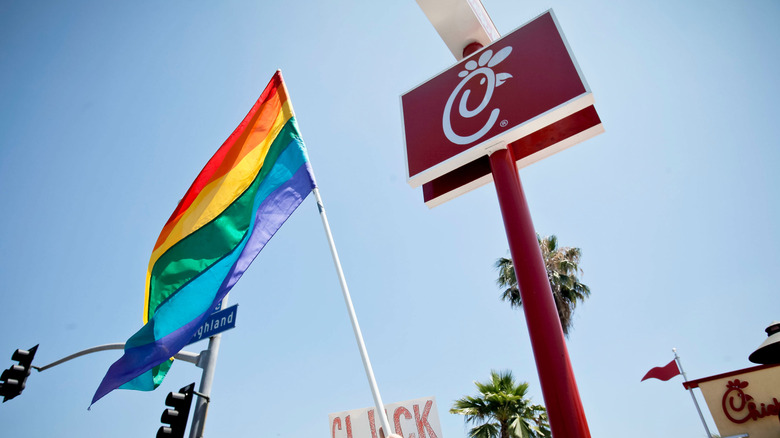 A rainbow flag in the air at a protest outside a Chick-fil-A