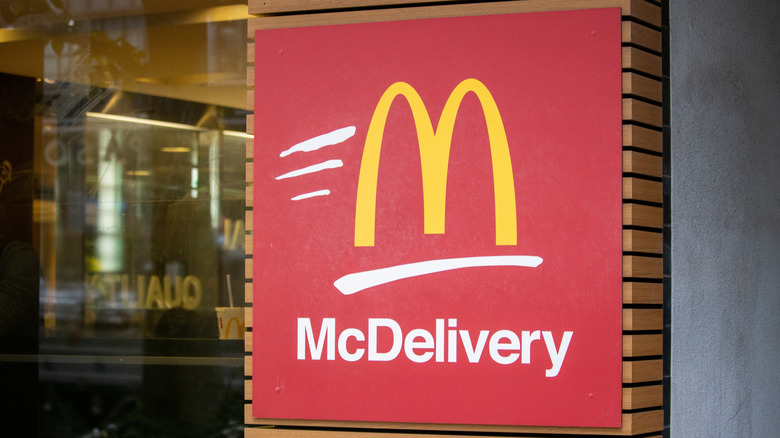 A red McDelivery sign with the Golden Arches logo and movement lines