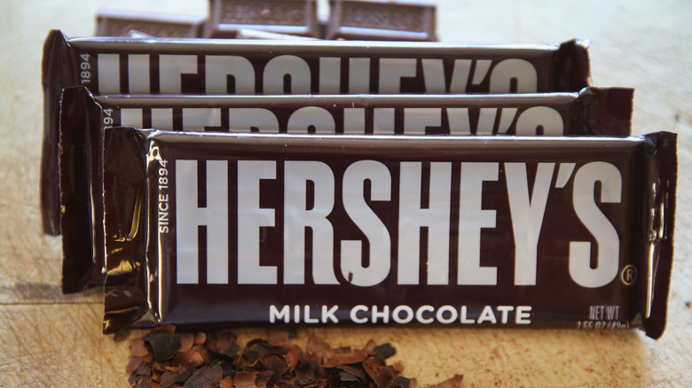 Three Hershey chocolate bars with loose chocolate pieces