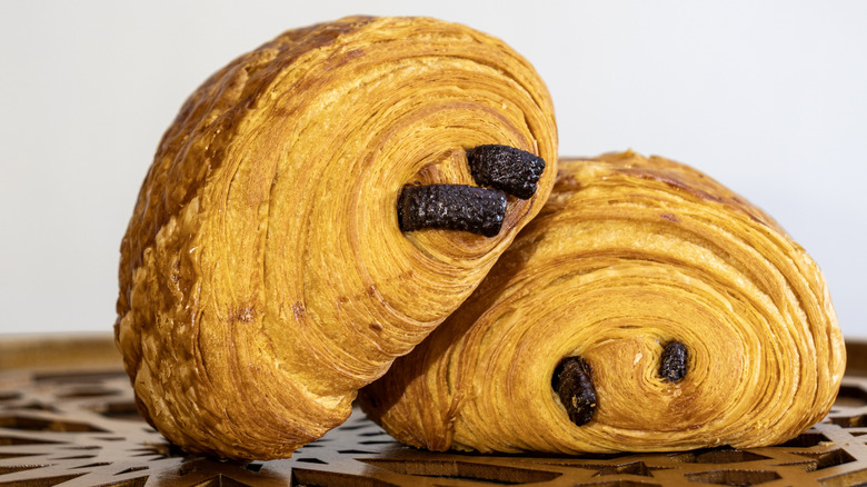 Two chocolate croissants on wooden surface