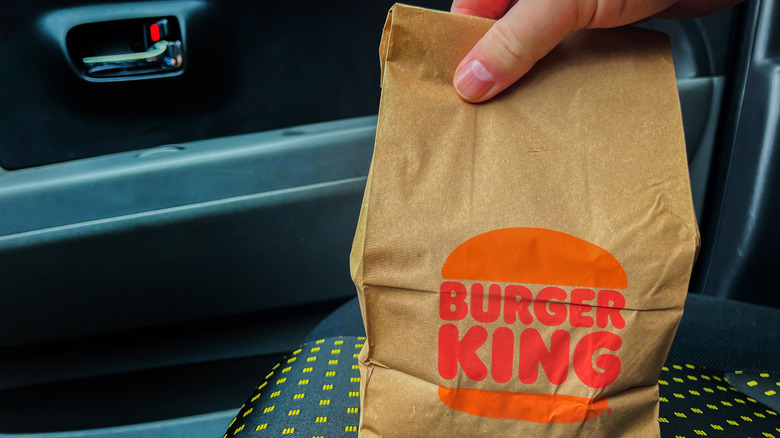 Burger King takeout bag held by hand in car