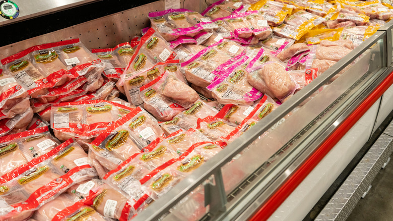 Packages of raw Kirkland chicken breasts in a large open cooler