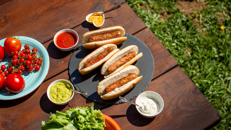 Hot dogs on picnic table with toppings